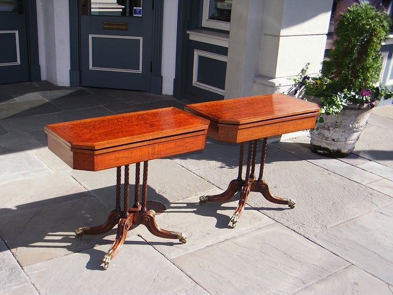 Pair of English plumb pudding flip top mahogany game tables cross banded with a Satinwood skirt, ebony string inlay, supported by classical twisted columns, and terminating on scrolled legs with the original filigree lions paw brass casters.  Late