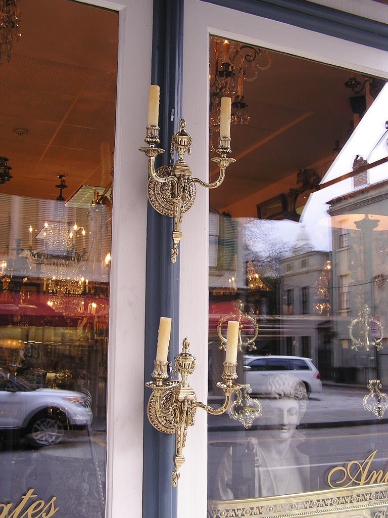 Pair of French two arm brass wall sconces with centered urn, chased fluting, bell flowers, and floral swags, Originally candle powered. Dealers please call for trade price.