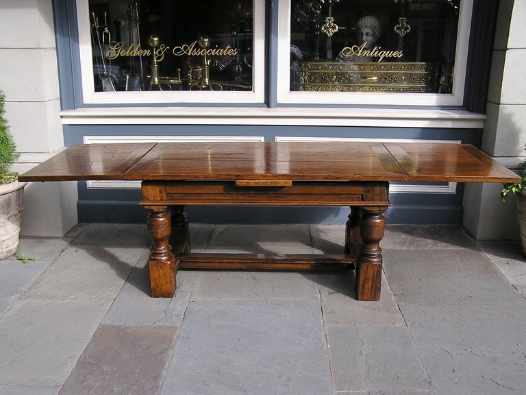 French early Oak two leaf farm table with carved skirt,  turned bulbous legs, centered cross stretcher, and terminating on original block feet. Table adjust from five feet to nine feet when extended. Early 19th Century