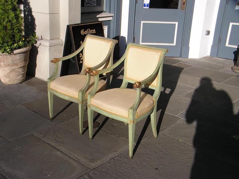 Pair of Regency Italian painted and gilt dolphin arm chairs with floral medallions, stripped upholstery with gold piping, and terminating on frontal tapered and rear splayed legs.  Dealers please call for trade price.