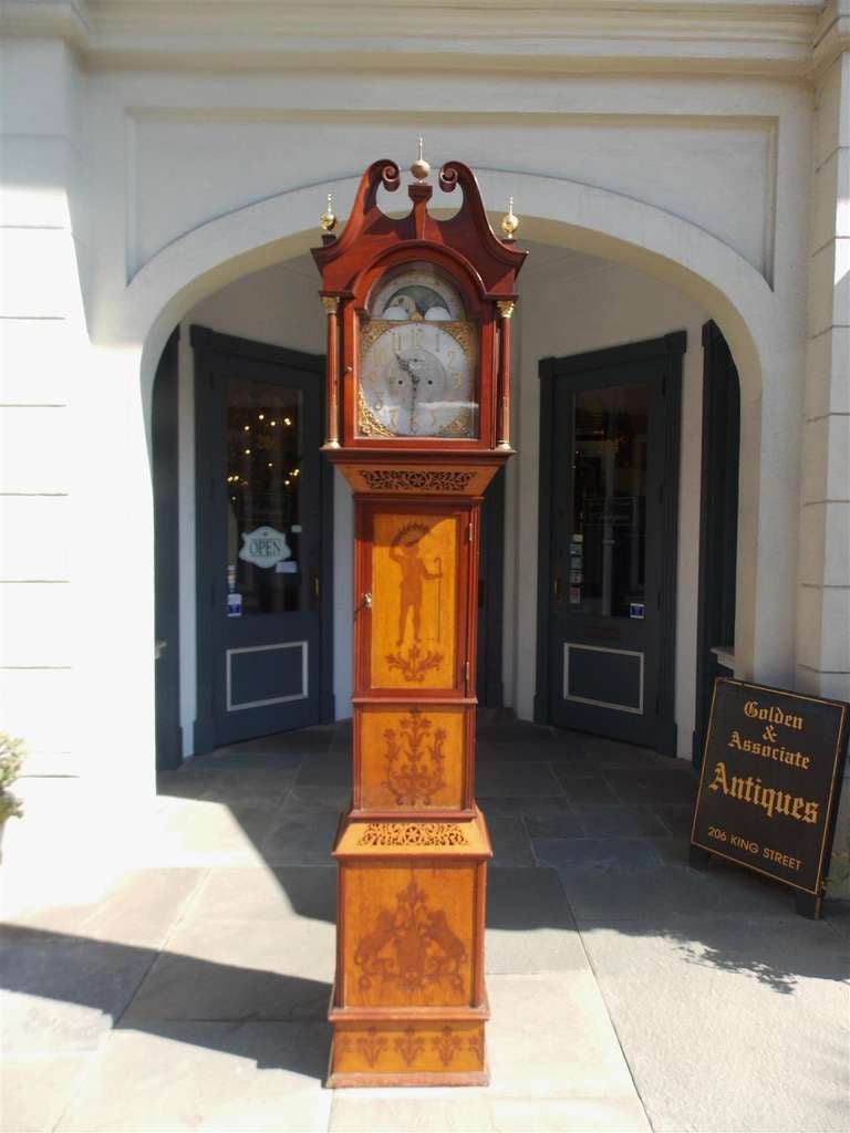 English mahogany tall case clock with scrolled pediment, brass finials, Corinthian columns, and intricate inlaid motif. Mid 19th Century