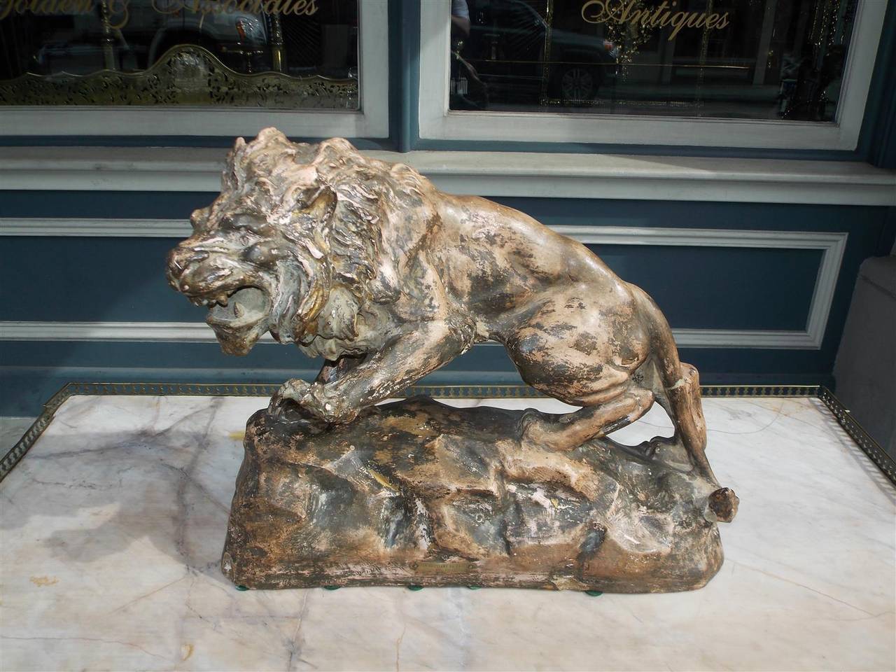 French Terracotta roaring lion mounted on rocky rectangular plinth.  Plaque reads Lion Guettant Sa Proie, Par Foucher.  Late 19th Century