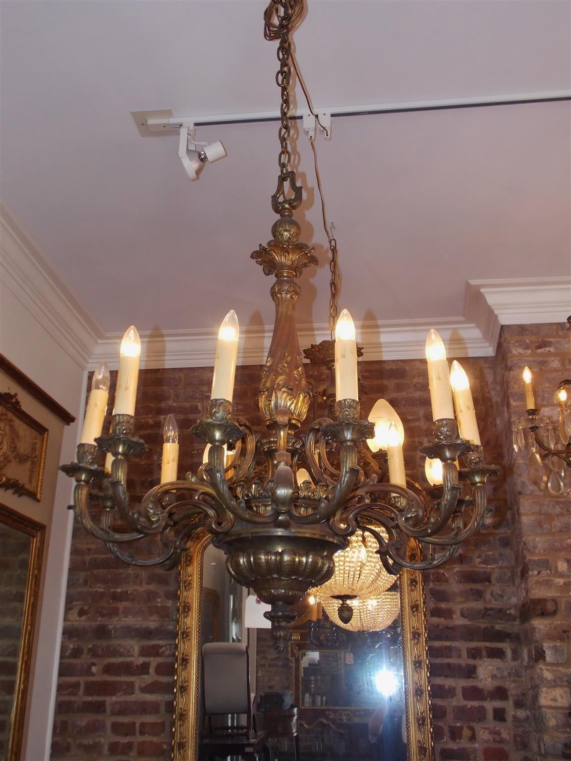 French gilt bronze twelve-light chandelier with centered bulbous decorative floral column, acanthus scrolled arms, terminating on circular gadrooned bulbous finial. Originally candle powered and has been electrified, Mid 19th century.