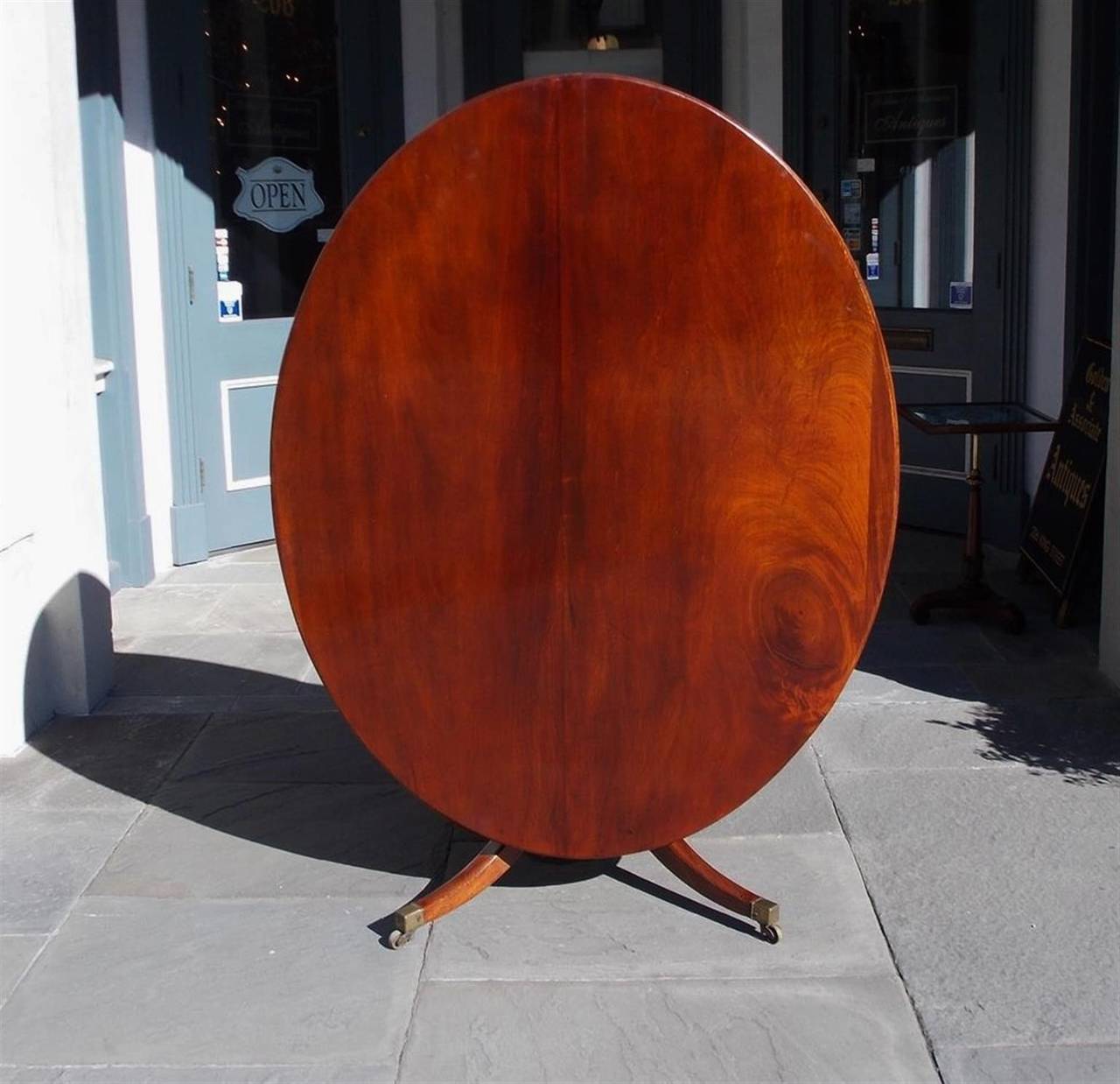 English Regency mahogany tilt top breakfast table with turned bulbous ringed pedestal, original locking mechanism, and terminating on saber legs with original brass casters. Late 18th Century