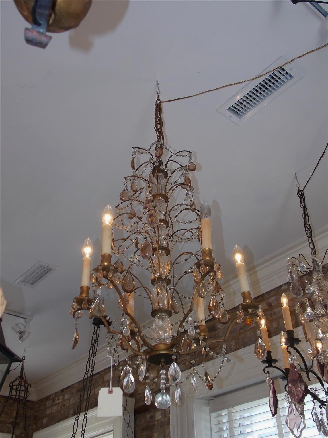 Lampadario francese in bronzo dorato e cristallo ambrato a sette livelli con colonna centrale in cristallo e perline intrecciate tra i bracci.  Originariamente alimentata a candele, è stata elettrificata.  Inizio del XIX secolo.
