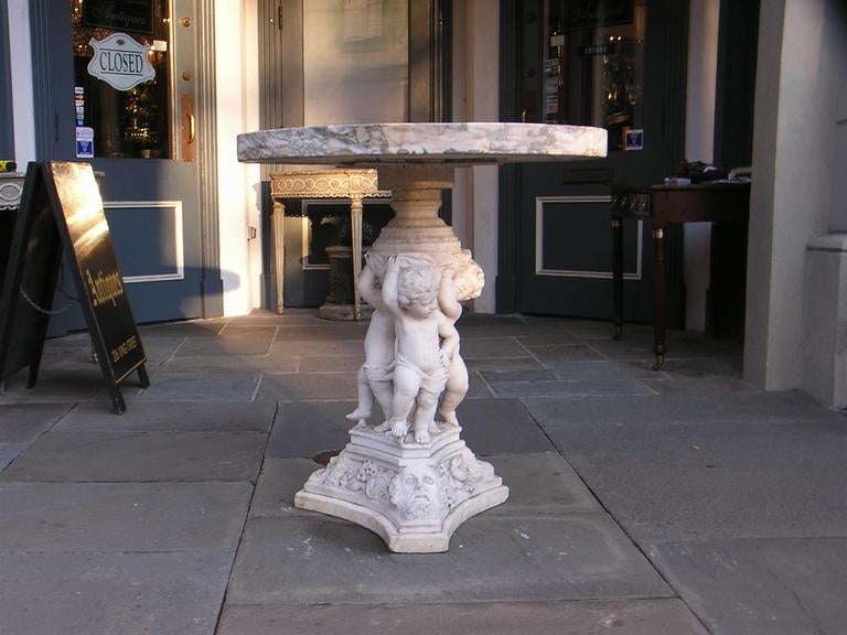 Italian marble pedestal table with circular top, carved cherub centered pedestal, and terminating on triangular base with  mythological figures, lyre, fruit, and chalice motif.  Dealers please call for trade price. 