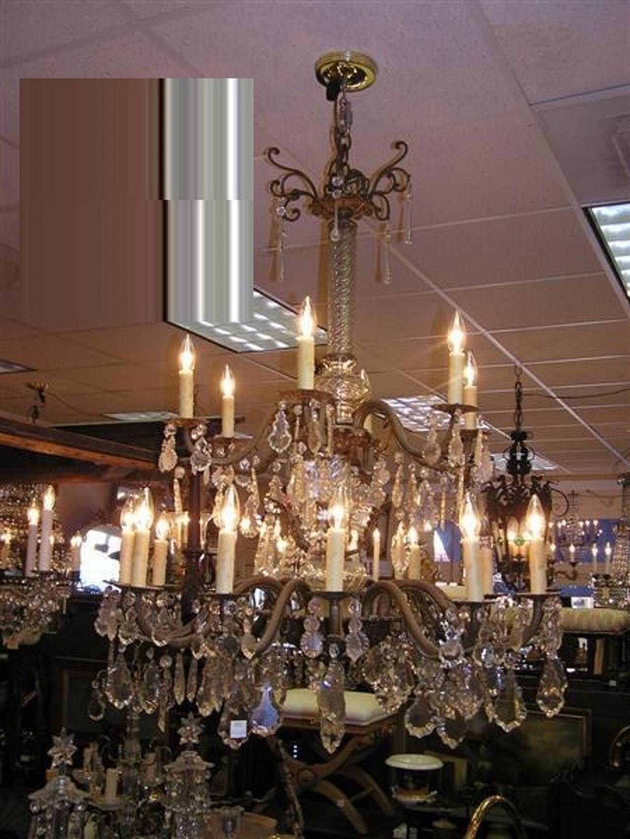 Lustre français en bronze doré et cristal à deux niveaux et dix-huit lumières, avec une tige centrale en spirale à bulbe de cristal, des bras cannelés à volutes florales et une base à médaillon floral, 19e siècle. Alimenté à l'origine par des
