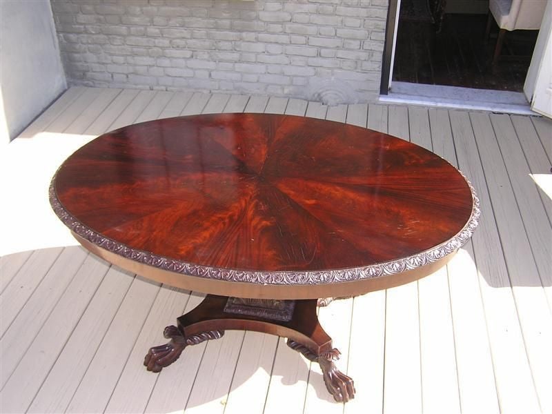 American mahogany oval library table with carved acanthus leaf pedestal and lions paw feet. Attributed to Anthony Quervelle. Early 19th Century. 