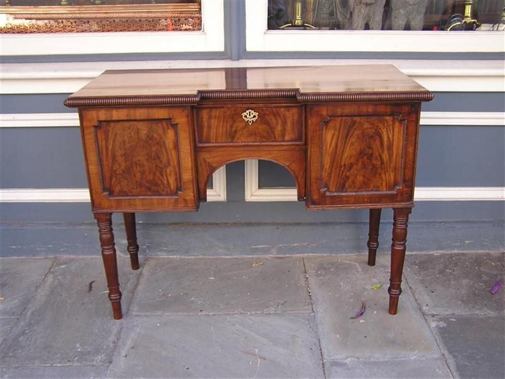 English mahogany brandy board with gadrooned molded edge top, flanking cabinet door and drawer, centered drawer, and terminating on bulbous ring legs.  Early 19th Century. 

