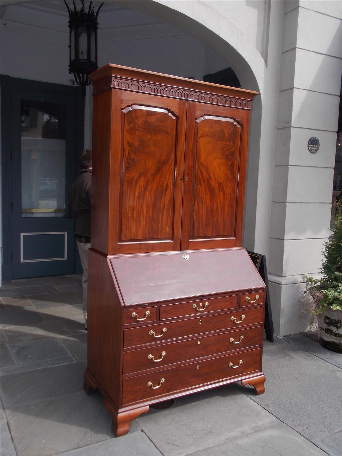 English Chippendale mahogany blind door secretary with bookcase.  Upper case has a carved cornice fret work with flanking blind doors concealing interior adjustable shelving.  Lower case has a slant front desk with fitted interior drawers, pigeon