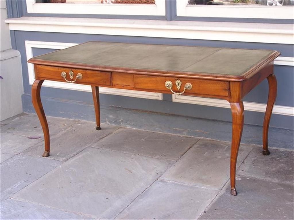 French Cherry library table with a leather top writing surface, two sliding drawers, original brasses, and terminating on cabriole legs with hoof feet. table is finished on both sides with faux drawers and brasses.  Late 18th Century