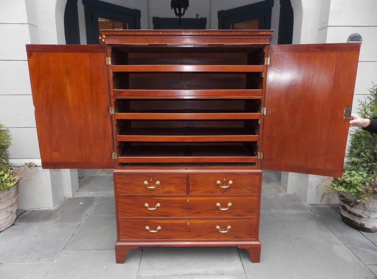 American Chippendale mahogany linen press with upper case book matched flanking doors over four graduated lower case drawers.  Press has a carved molded cornice and oval panels with satinwood string inlay and cross banding.  The piece also retains
