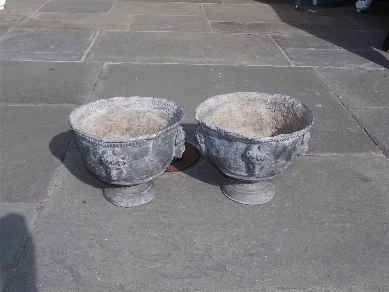 Pair of Italian lead garden urns with single row of beading, figural heads, and resting on circular base, Early 19th century.