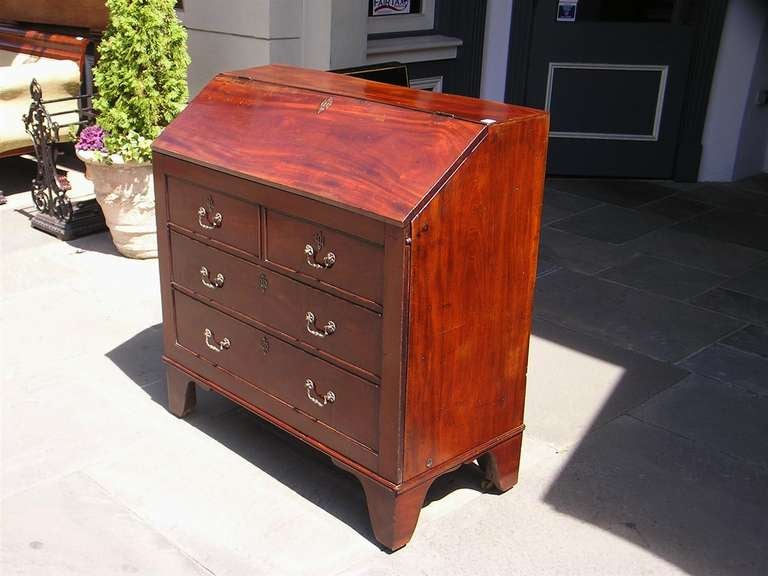 English mahogany campaign hinged slant front bureau / bedstead with removable faux drawer front panel with the original brasses and escutcheons, fitted interior with a folding bedstead on feet, and terminating on bracket feet with the original brass