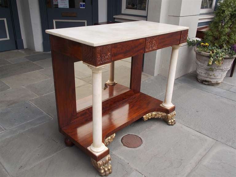 American mahogany marble top pier table with carved acanthus floral edge,  marble corner columns, original mirror, and terminating on gilded carved floral lions paw feet. Philadelphia. Early 19th Century