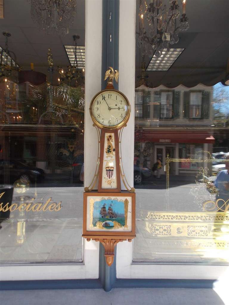 American Walnut banjo clock with original brass eagle finial, eglomise paintings,         and signed painted face under glass dome.  Waltham, Mass. 19th Century.
Clock is in working condition.