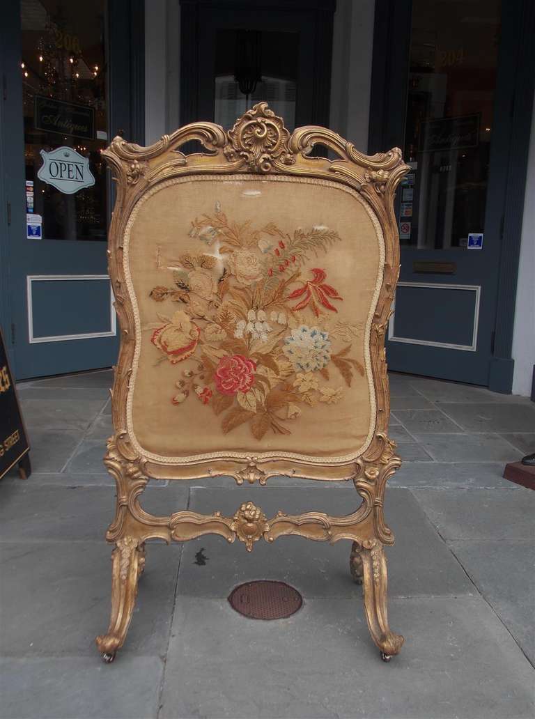 French carved wood and gilt floral fire screen with original abusson insert  terminating on scrolled cabriole legs with the original brass casters.  18th Century