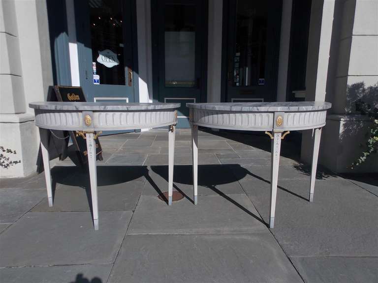 Pair of Italian faux painted and gilt consoles with oval floral medallions, fret work, and terminating on tapered legs with bell flower motif.  19th Century