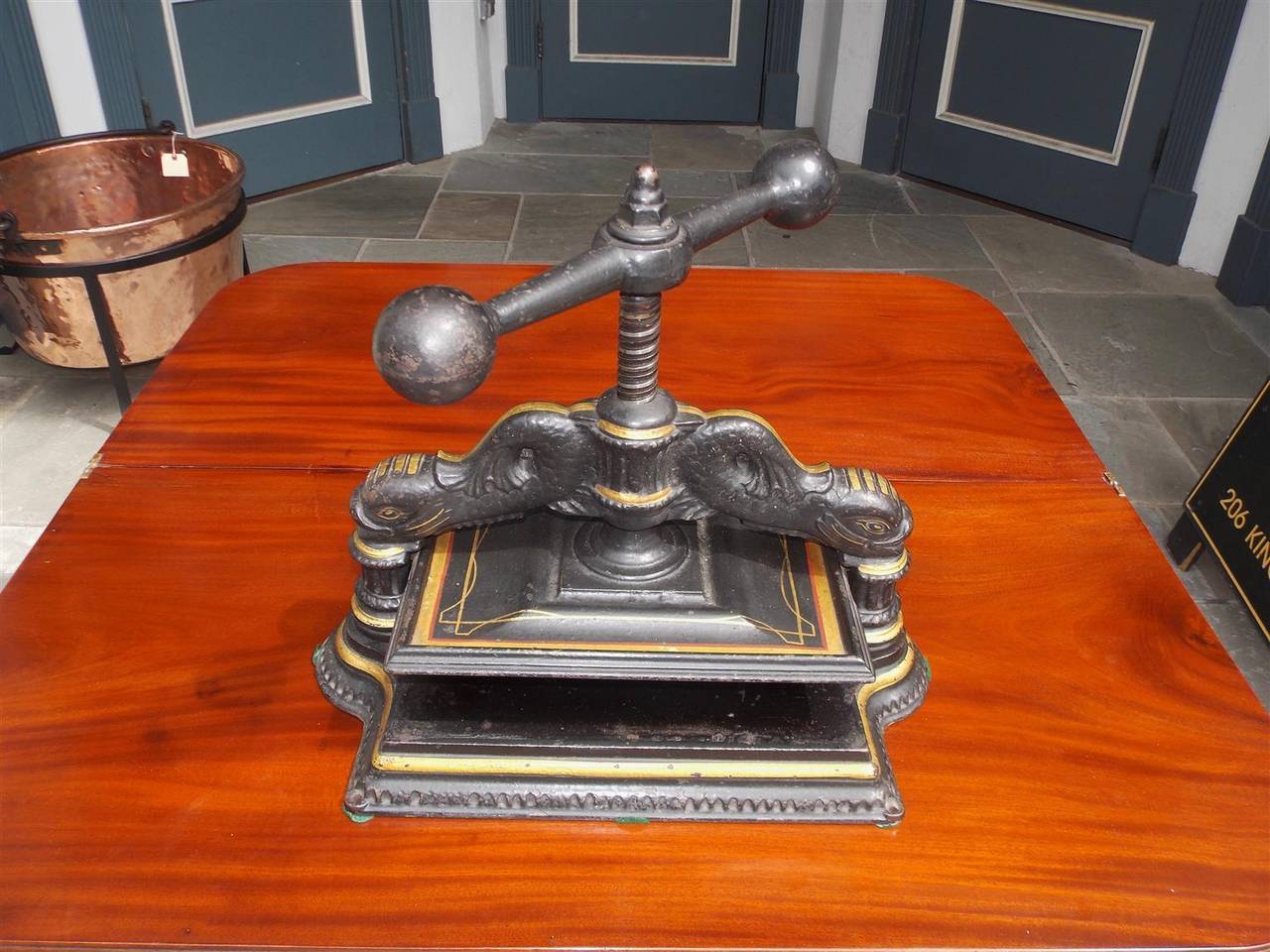 English Regency cast iron and gilt flanking dolphin book press with adjustable bulbous turned handle and resting on decorative rectangular plinth.  Mid 19th Century.