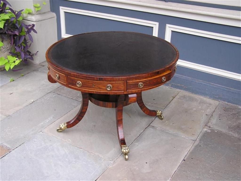 English Rosewood and Yew wood leather top rent table with original brass casters. Table rotates on brass barrel wheels.