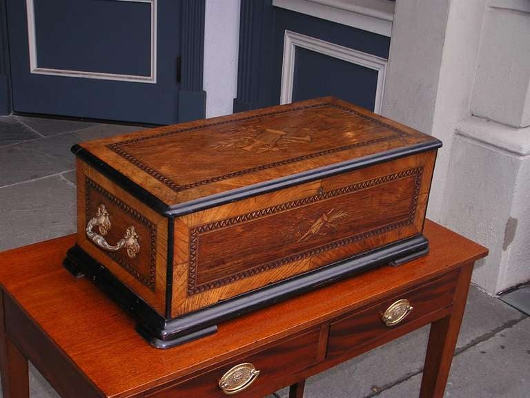 German inlaid and ebonized music box with original musical works, gilded ornate side handles, and terminating on block feet.  Music box is in working condition.  Mid 19th Century