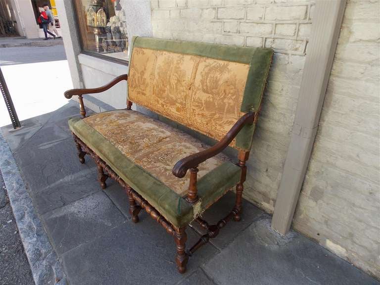 French Walnut settee with scrolled carved acanthus arms, original silk tapestry, and terminating on turned bulbous legs with stretchers.  Dealers please call for trade price.