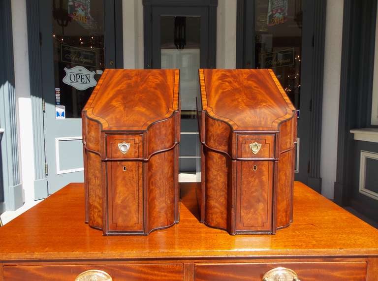 Pair of English crotch mahogany slant top cutlery boxes with original inserts, ebony string inlay, and silver over brass mount shield back escutcheons.  Late 18th Century