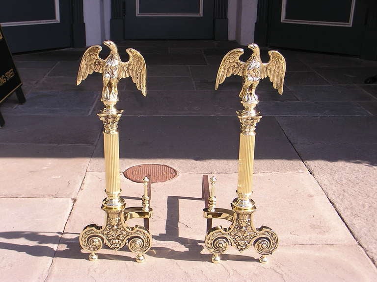 Pair of American brass andirons with perched eagles on top of ball finials, reeded Corinthian plinths, and terminating on scrolled foliage legs with ball feet and original finial log stops. Dealers please call for trade price.