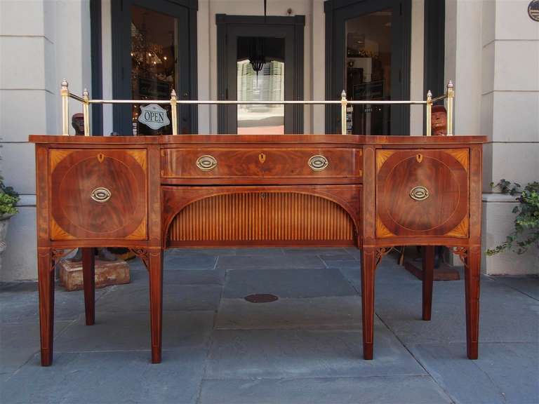 English Hepplewhite mahogany three drawer sideboard with flanking doors, Satinwood patera inlay, carved corner fret work, original brass gallery, and terminating on tapered legs. Sideboard has inlaid diamond  escutcheon concealing  potty cupboard