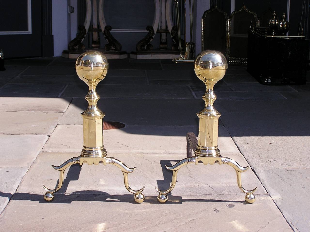 Pair of American brass ball top ribbed andirons with turned bulbous faceted plinths, scalloped skirts, spurred legs, and terminating on ball feet. 
 Boston, Circa 1800.