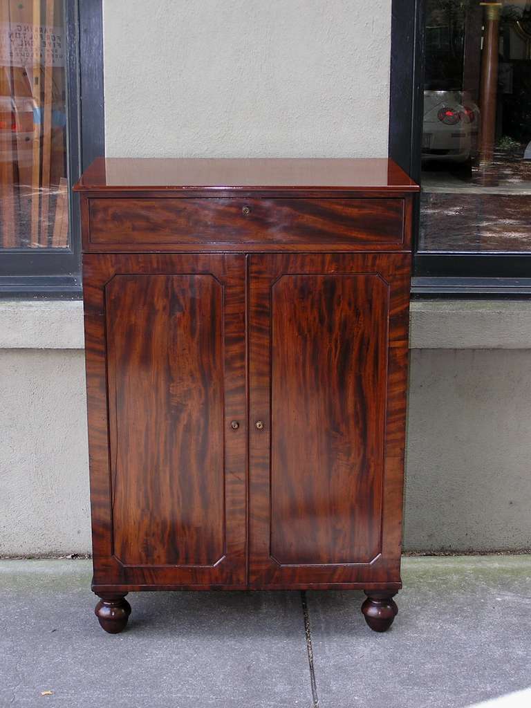 English mahogany one drawer linen press with lower two door cabinet revealing original pull out shelves, and terminating on stylized bun feet.  Early 19th Century.