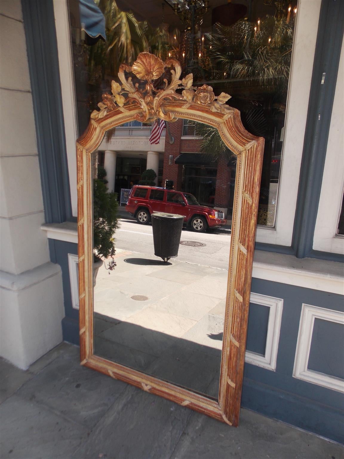 French gilt carved wood and red lacquer wall mirror with floral shell motif, bead work, and surrounded by reeded banded corner cut molded edges. Mirror retains the original glass and wood back. Early 19th Century.