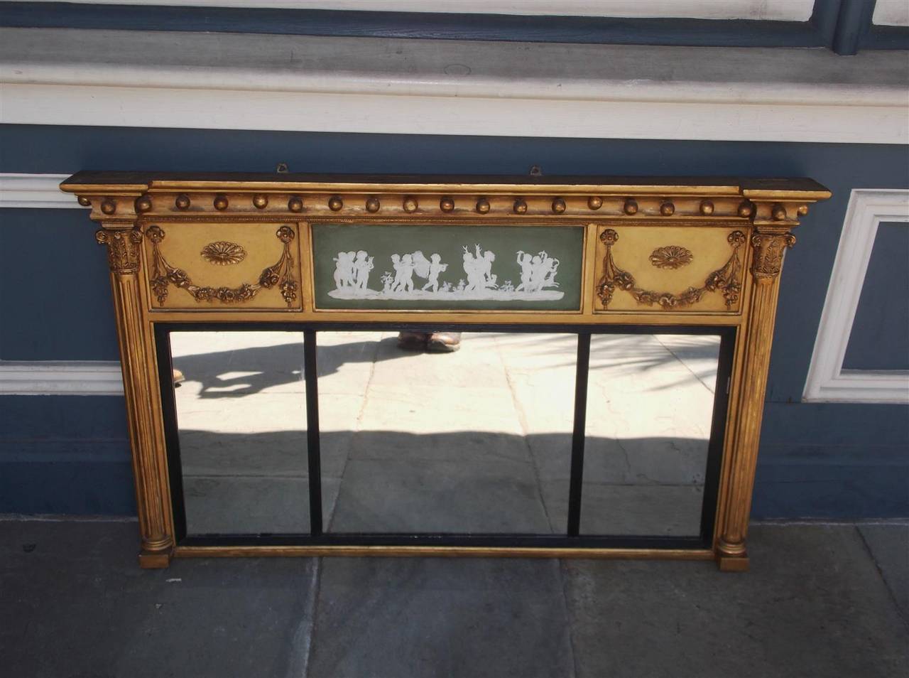 English gilt carved wood over mantel mirror with ball finials, centered jasper ware panel depicting children celebrating after a successful hunt for wild game,  flanking medallion decorative floral swags, Corinthian side columns, and reeded ebonized