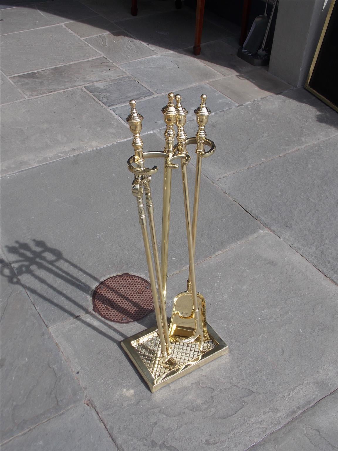 Set of American brass fire tools on stand with urn finial tops resting on squared decorative hand chased base.  Set consist of shovel, tong, and poker.  Late 19th Century.