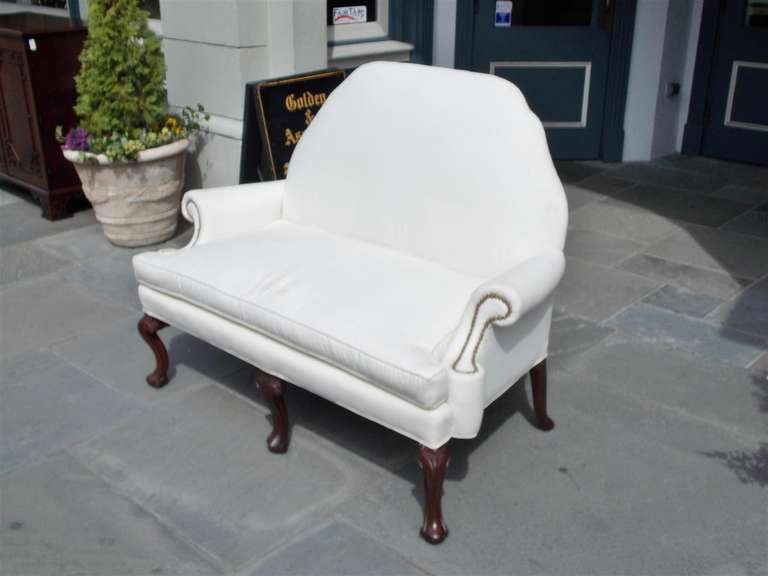 English mahogany camel back settee with flanking scrolled brass tacked arms, removable cushion, carved floral knees, and terminating on trifod splayed feet. Settee is upholstered in white muslin with horse hair and cotton padding, Early 19th century.