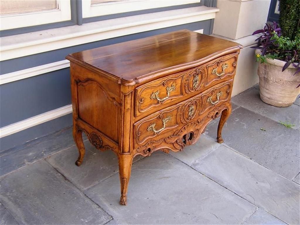 French Provincial two drawer Walnut chest with carved molded edge, outset corners, floral and shell decorative motif, original ormolu brasses, and terminating on the original cabriole floral feet.  Mid 18th Century

