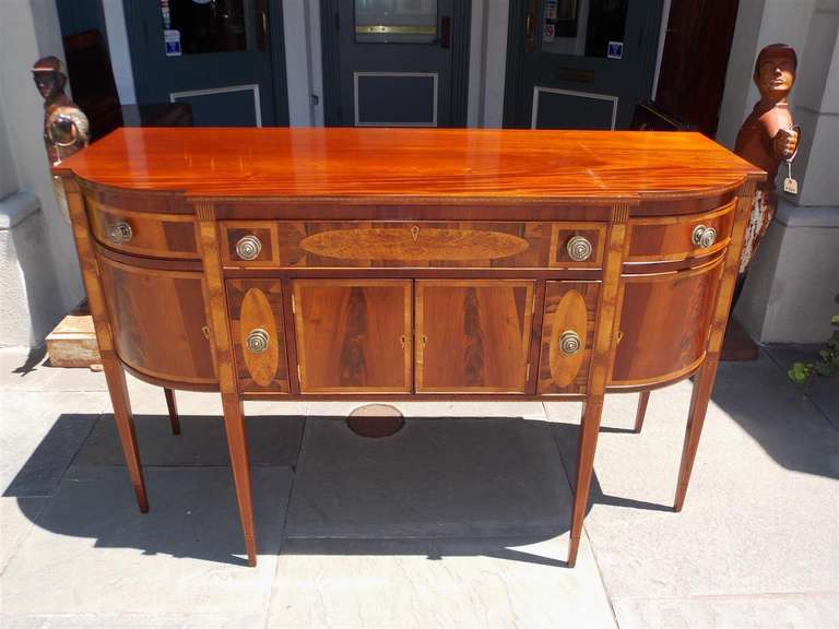 American mahogany tulip wood and satinwood inlaid five drawer sideboard with original brasses, upper and lower locking cabinets,  and terminating on tapered legs. Early 19th Century.