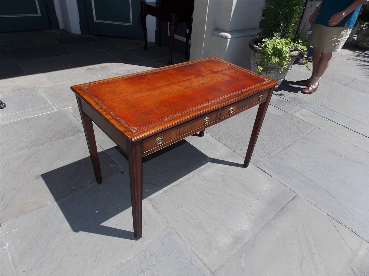 English mahogany two-drawer leather top writing desk with carved molded edge, original brasses and terminating on chamfered tapered legs,  Late 18th century. Desk is finished on all sides.