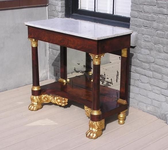 American flame mahogany marble top pier table with gilt carved capitals , flanking cornucopias, original mirror, and terminating on gilt acanthus lions paw feet. All original.  Early 19th Century.