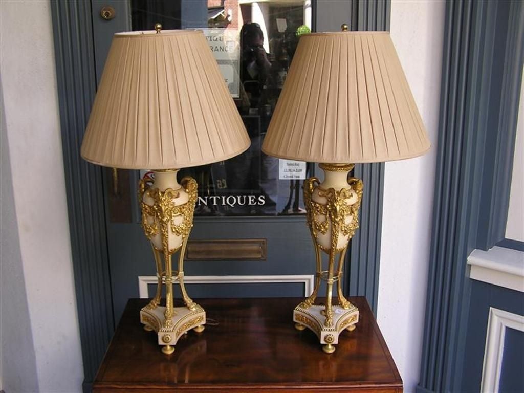 Pair of French cassolettes marble and ormolu bronze table lamps with rams head mounts, floral ribbon swags, hoof feet, and terminating on tripod base with decorative medallions and bun feet.  Early 19th Century.  
Pair of Lamps have a 18.5 diameter