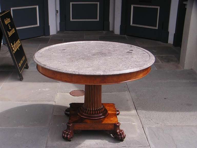 French mahogany marble top pedestal table with molded edge skirt, reeded center column,  and supported by a squared plinth with lions paw feet and original brass casters.  Early 19th Century