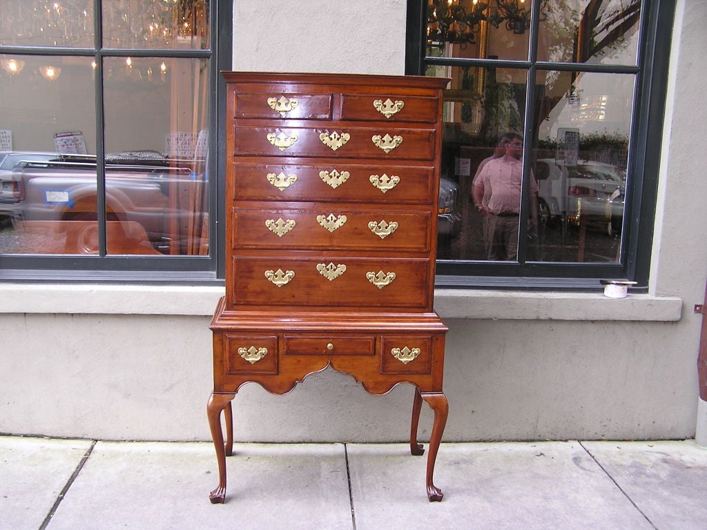 English walnut highboy on stand with a carved molded edge top , seven upper case graduated drawers with inlaid feather banding &  brasses , three lower case drawers with feather banding & brasses , carved scalloped skirts , and terminating on elbow