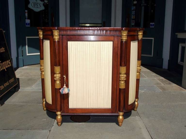 Italian rosewood and gilt three door console with gilt carved floral mounts, pleated upholstered wooden doors, and terminating on gilt bulbous feet.  Dealers please call for trade price. 