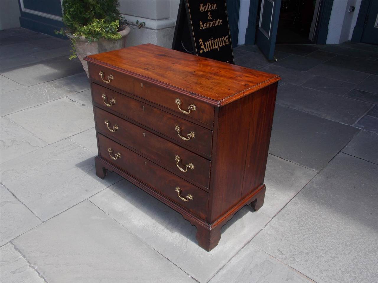 English Chippendale mahogany graduated four drawer bachelors chest with one board top, original brasses, and terminating on original bracket feet.  Mid 18th Century.