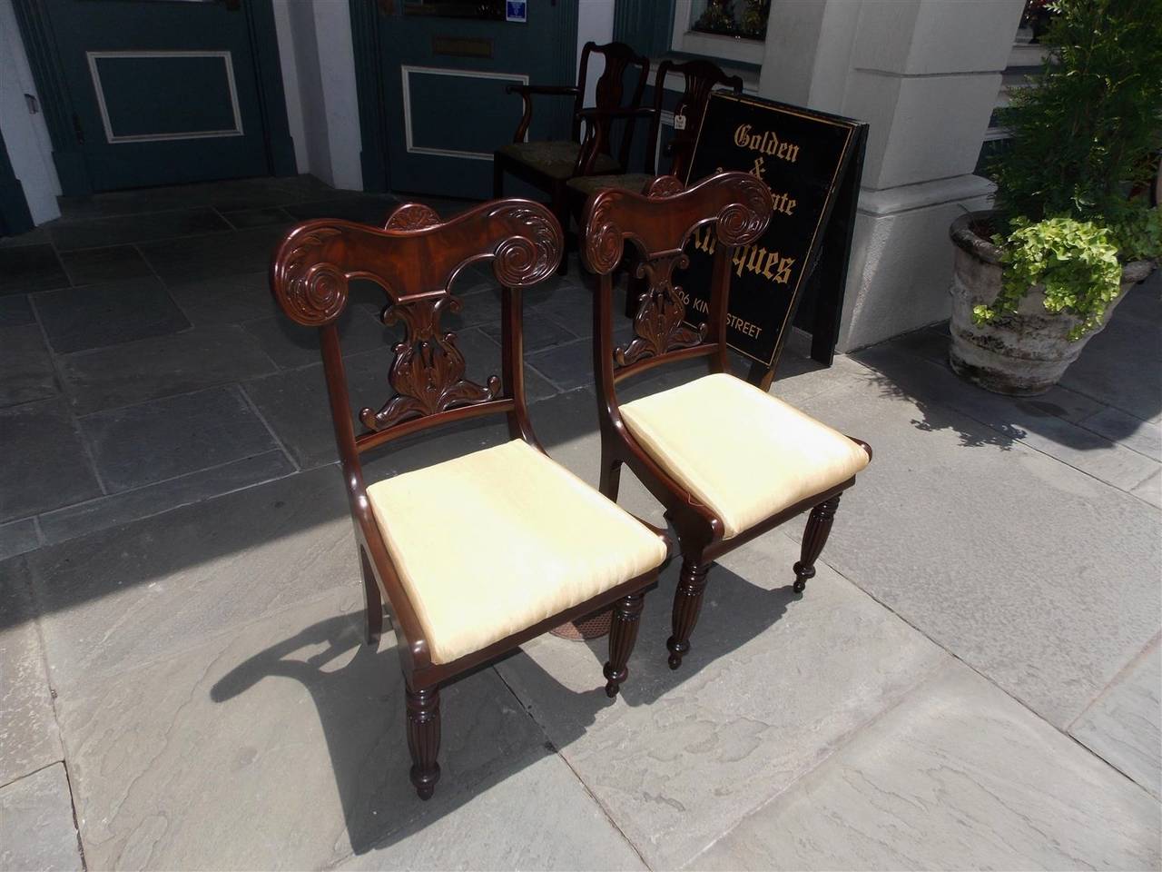 Pair of Caribbean mahogany side chairs with carved scrolled acanthus and floral splat backs, upholstered removable seats, and terminating on reeded bulbous legs, Early 19th century.