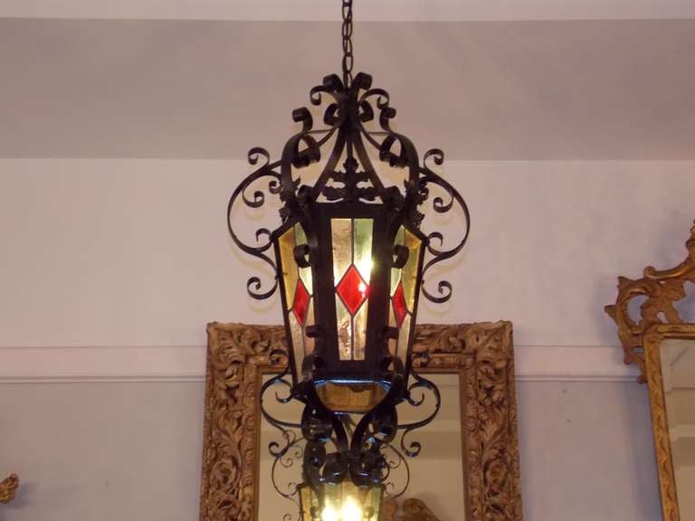 American scrolled foliage wrought iron and stained glass hanging hall lantern with three light interior cluster. Originally candle powered and has been electrified. Mid 19th Century