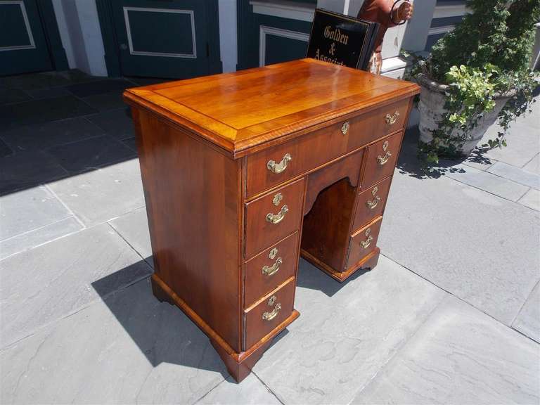 English walnut seven drawer knee hole desk with cross banded top, centered lower prospect door, and terminating on bracket feet. Late 18th Century