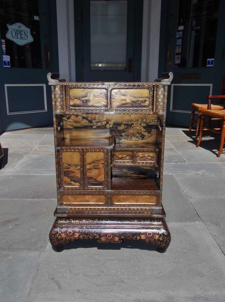 Japanese compartmentalized lacquered two drawer cabinet on stand with stenciled floral landscape scenes, hinged doors, hidden sliding compartments, and resting on decorative stand.  Mid 19th Century