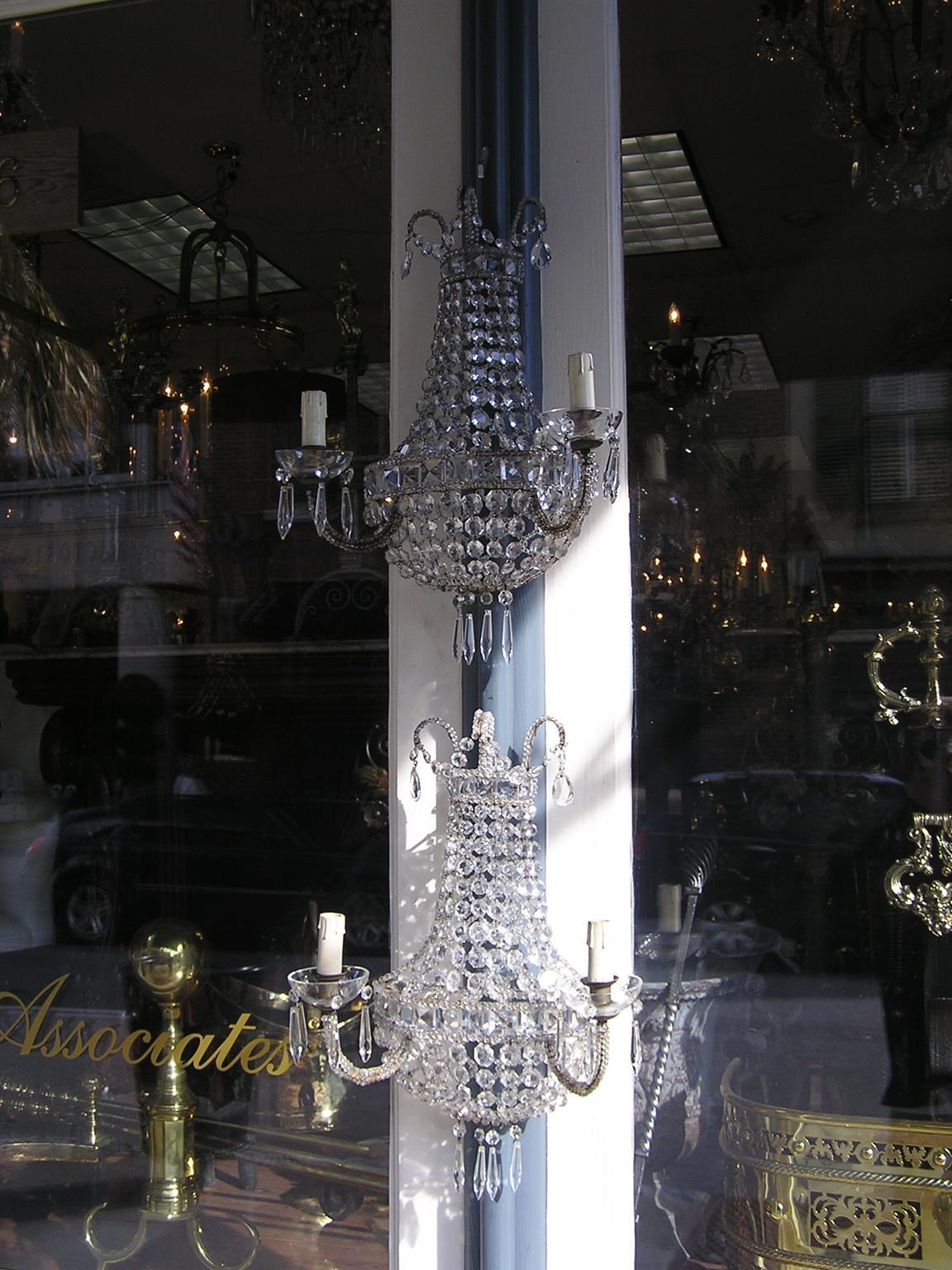 Zwei zweiarmige Wandleuchter aus französischer Bronze und Kristall mit dekorativer Perlenarbeit, kaskadenförmigen Prismen und originalen Kristallbobachen. Ursprünglich mit Kerzen betrieben, dann elektrifiziert, Mitte des 19. Jahrhunderts.