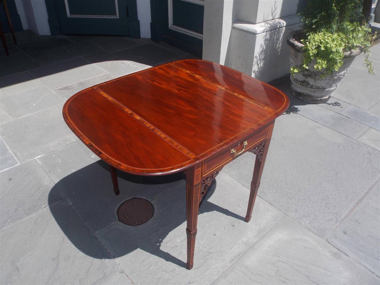 American mahogany and tulipwood one-drawer drop-leaf pembroke table with original brasses, carved corner fret work, satinwood string inlay, and terminating on tapered cuffed burled inlaid squared legs, VA, Late 18th century. Table is 37.75